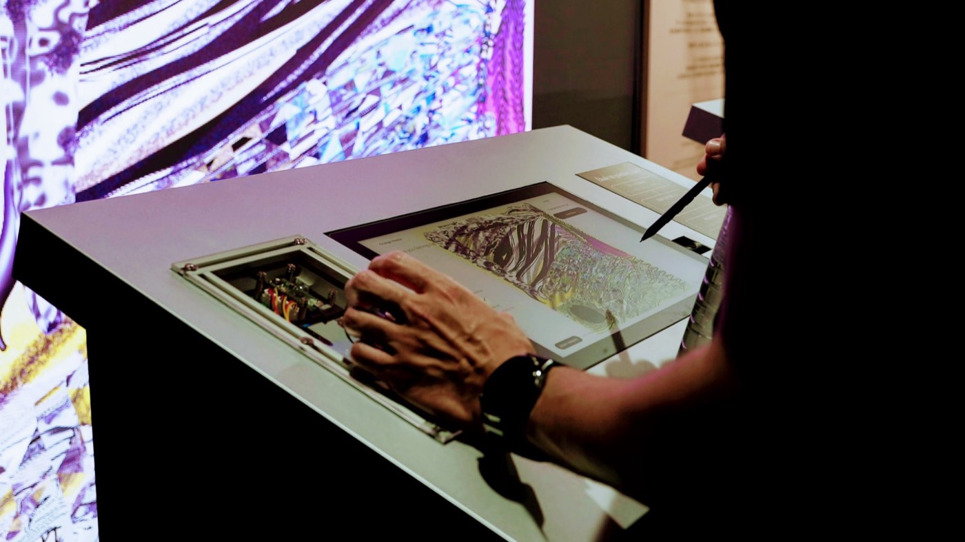 A visitor drawing with a pen on the installation's tablet.